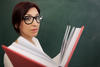 Teacher holding a book in front of the chalkboard