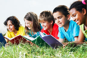 line of kids lying in the grass reading books