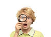 Boy looking through magnifying glass with surprised look on his face