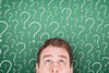Chalkboard of question marks behind young man