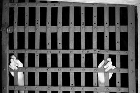 hands reaching through a jail wall