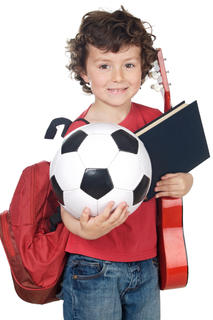 Young boy carrying a guitar and soccer ball