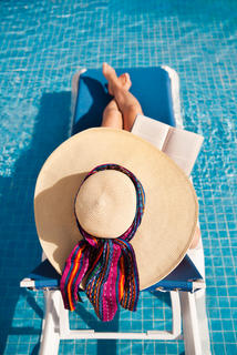 Woman lounging by the pool reading a book